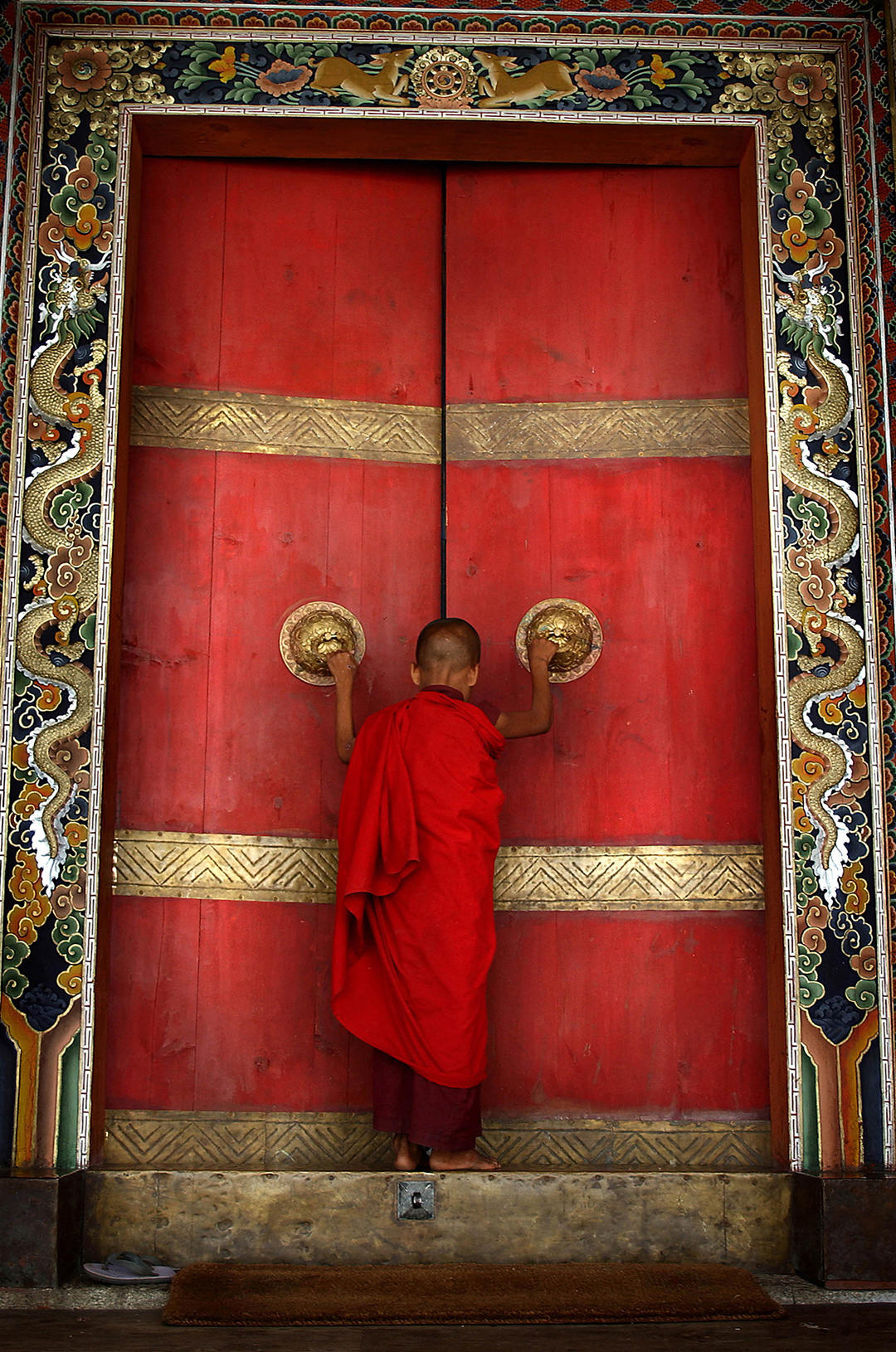 BHUTAN:THE LAST SHANGRI LA 2: A Buddhist monk enters the formidable doors of Trongsa Dzong, the Ancestral home of Bhutan? monarchy. The Himalayan kingdom of Bhutan has sat in isolation for thousands of years and only recently has been thrust into the glare of modern times after centuries of solitude. Bhutan is a tiny, remote, and impoverished country wedged precariously between two powerful neighbors, India and China. Violent storms coming off the Himalaya gave the country its name, meaning "Land of the Thunder Dragon." This conservative Buddhist kingdom high in the Himalaya had no paved roads until the 1960s, was off-limits to foreigners until 1974, and launched television only in 1999 .