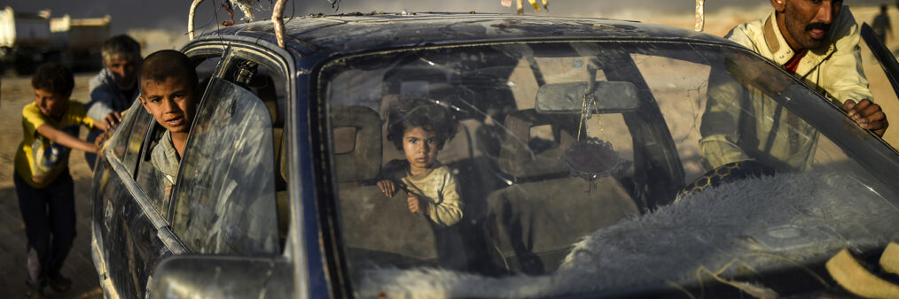 AFP 18 / IRAK 22 octobre 2016 - Qayyarah, Irak - Un père et ses deux enfants arrivent dans un centre pour réfugiés alors que plus de 10 000 Irakiens ont déjà fui leur foyer depuis le début de l’offensive terrestre qui a commencé le 17 octobre. L’épaisse fumée noire qui s’élève à l’horizon provient des champs de pétrole qui ont été incendiés par le groupe État Islamique. AFP / BULENT KILIC