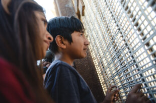 Un jeune mexicain parle avec sa mère à travers le mur séparant le Mexique des Etats-Unis à San Diego, Californie, mai 2017